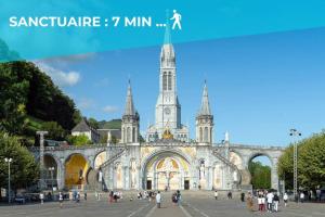 un gran edificio con una torre de reloj delante de él en Le Jungle - Lourdes - Proche Sanctuaire, en Lourdes