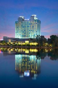 un grand bâtiment avec sa réflexion dans l'eau dans l'établissement Adana HiltonSA Hotel, à Adana