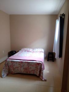 a small bedroom with a bed with a pink blanket at Apê perto do Parque Euclides Dourado in Garanhuns