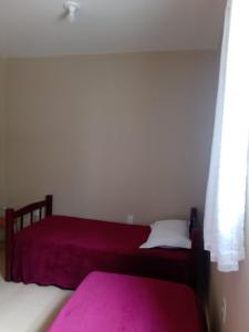 two beds in a room with pink sheets and a window at Apê perto do Parque Euclides Dourado in Garanhuns