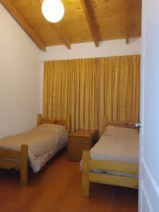 1 dormitorio con 2 camas y una ventana con cortinas en Muy Patagónica, Casa de Campo en Trelew