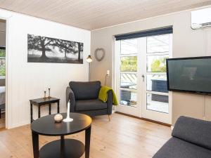 un soggiorno con TV, sedia e tavolo di Holiday home Grenaa LI a Grenå