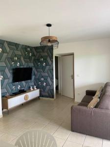 een woonkamer met een bank en een flatscreen-tv bij Monvert Evazion in Le Robert