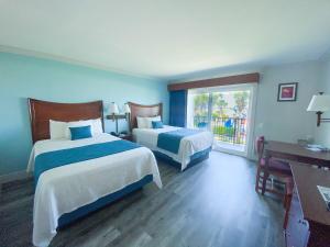 Habitación de hotel con 2 camas y ventana en Seahorse Oceanfront Inn, en Neptune Beach
