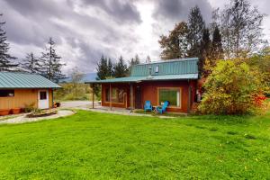 a small house with a green roof and a yard at Rocky's Log Cabin & Retreat in Sultan