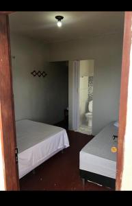 a room with two beds and a bathroom with a toilet at Pousada Lua Branca in Tutóia
