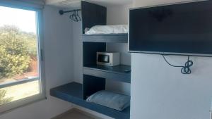 Habitación con estanterías azules, TV y ventana. en Mar y Laguna en José Ignacio