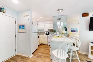 a kitchen with white cabinets and a table and chairs at Gulf Highland, Unit A in Panama City Beach