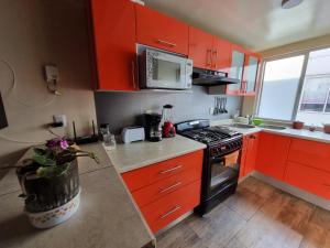 een keuken met rode kasten en een fornuis met oven bij Bonito departamento familiar in Mexico-Stad