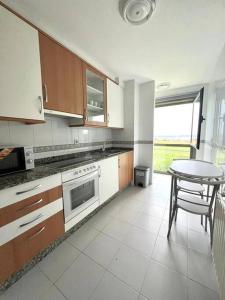 a kitchen with a table and a table and a chair at BaruHaus piscina y parking Rianxo 1 in Rianjo