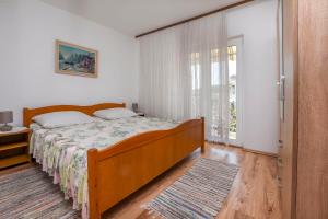 a bedroom with a bed and a large window at Apartments Karleusa in Rogoznica