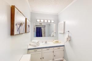 a white bathroom with a sink and a mirror at A Place Between the River and Sea in North Topsail Beach