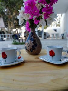 a table with two cups and a vase with flowers at Henchir ejdoud in Kairouan