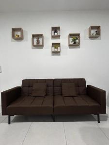 a brown couch sitting in front of a white wall at Armadale Residence-Gala City in Kuching