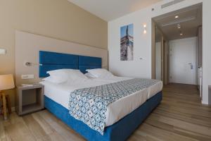 a bedroom with a large bed with a blue headboard at Romana Beach Resort in Makarska