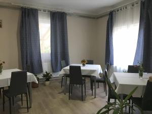 un comedor con mesas y sillas blancas y cortinas azules en Vállaj Vendégház, en Vállaj