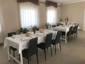 Un comedor con mesas blancas y sillas negras. en Vállaj Vendégház, en Vállaj