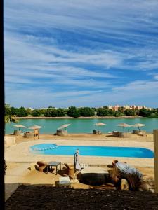 a swimming pool with a body of water with umbrellas at West golf 2bedroom in Hurghada