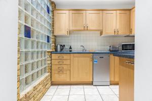 uma cozinha com armários de madeira e uma máquina de lavar louça branca em Central 2Bed Mew in Marylebone em Londres