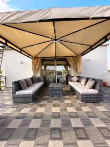 eine Terrasse mit zwei Sofas und einem großen Sonnenschirm in der Unterkunft 2BD Apartment in a rooftop with a private terrace in Kairo