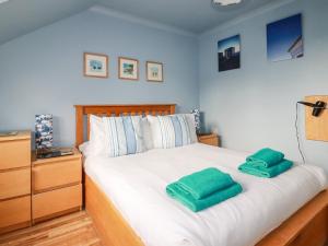 a bedroom with a bed with two green towels on it at Sunflower Cottage in Wadebridge