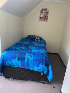 a bedroom with a bed with a blue comforter at Casa Parque Rauquen in Curicó