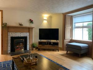 a living room with a fireplace and a flat screen tv at Ivy Cottage, Aberfeldy - Highland Perthshire in Aberfeldy