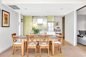 uma cozinha e sala de jantar com uma mesa de madeira e cadeiras em Waterfront Resort-Style Living at Glenelg Beach em Glenelg