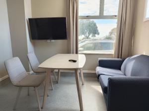 een woonkamer met een tafel, een bank en een tv bij Napier Art House Backpackers in Napier