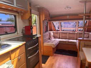 Kiwi Caravan Experience في موتويكا: مطبخ فيه موقد و كنب في فان