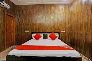 a bedroom with a bed with red pillows on it at Hotel Parvesh in Farrukhnagar