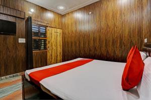 a bedroom with a bed with red pillows and wooden walls at Hotel Parvesh in Farrukhnagar
