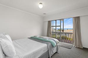 ein Schlafzimmer mit einem Bett und einem großen Fenster in der Unterkunft Woodward House Taupo in Taupo