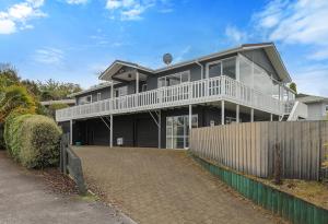 ein großes Haus mit einem Zaun davor in der Unterkunft Woodward House Taupo in Taupo
