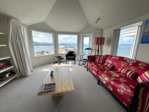 a living room with a red couch and a table at Super large seaview house in Wellington