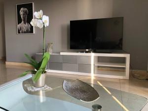 un salon avec une télévision et une table fleurie dans l'établissement Forum Ocean View Apartment, à Funchal