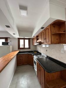 une cuisine avec des placards en bois et un comptoir noir dans l'établissement Mar y Cielo, à Necochea
