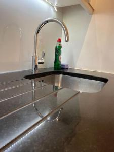 a kitchen sink with a green bottle on it at Cozy Modern Apartment in Croydon Central in Croydon