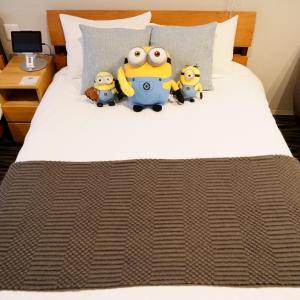 three toy minions sitting on top of a bed at Koti Sopo Universal Bay 4 by Liaison in Osaka
