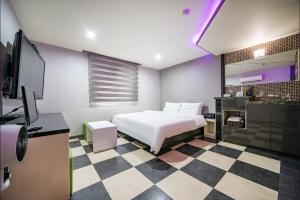 MU HOTEL في بوسان: غرفة نوم بسرير ابيض وارضية مضلمة
