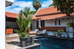 a villa with a swimming pool in front of a house at Luxurious Residence Rawai in Phuket Town