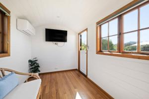 a living room with a tv on the wall and windows at Camp Crusty Eldorado in Eldorado