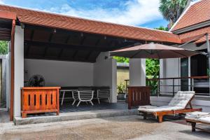un patio con sombrilla, sillas y mesa en Luxurious Residence Rawai, en Phuket