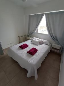 a bedroom with a white bed with red towels on it at Departamento del centro in Neuquén