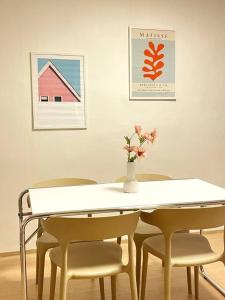 une table blanche avec des chaises et un vase avec des fleurs dans l'établissement Cozy U, à Daejeon