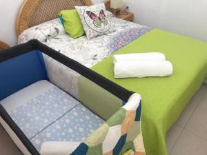 a bed with a green table with a chair and towels at VV YELYMAR. PLAYA DE ALOJERA in Alojera