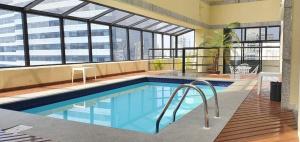 a large swimming pool in a building with windows at The Time Flat - Berrini - 200 metros do WTC in Sao Paulo