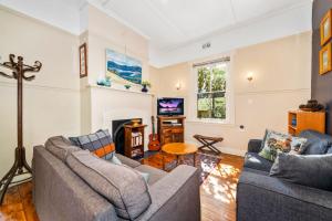a living room with two couches and a fireplace at Brigalow Cottage in Leura