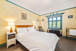 a bedroom with a large white bed and a window at Brigalow Cottage in Leura