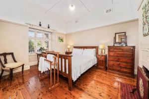 une chambre avec un lit, un bureau et une chaise dans l'établissement Brigalow Cottage, à Leura 6 autres photos